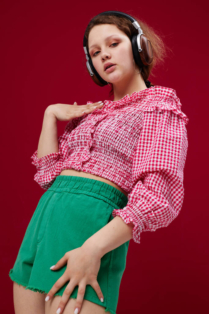 χαριτωμένο νεαρό κορίτσι σε πολύχρωμα ρούχα θέτοντας μουσική με τα ακουστικά αναλλοίωτα - Φωτογραφία, εικόνα