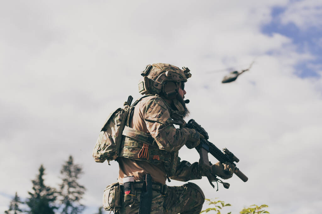 Oorlogsconcept. Een bebaarde soldaat in een Special Forces uniform die vecht tegen een vijand in een bosgebied. Selectieve focus. Hoge kwaliteit foto - Foto, afbeelding