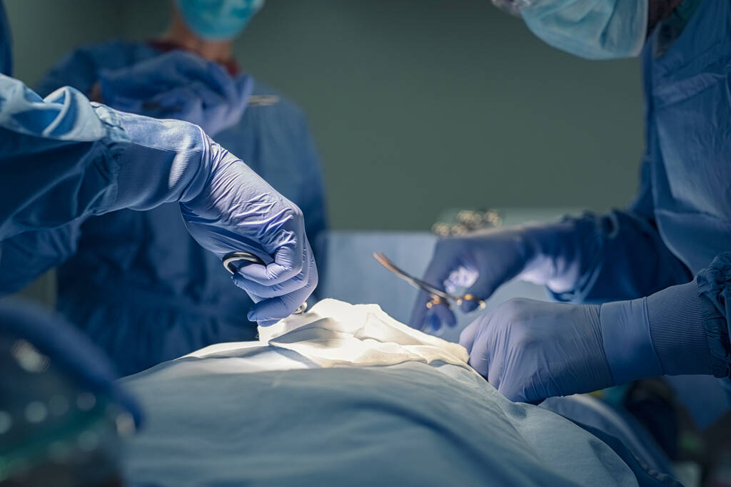 Zamknąć ręce zespołu medycznego wykonującego operacje w sali operacyjnej. Grupa chirurgów pracujących w sali operacyjnej ratująca życie pacjenta. Szczegóły dotyczące grupy lekarzy rąk i pracowników służby zdrowia posiadających instrumenty medyczne i pracujących w operatynie - Zdjęcie, obraz