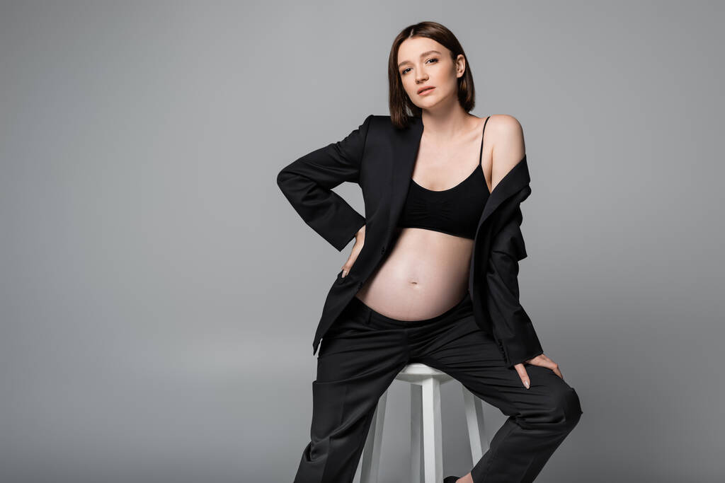 若いです妊娠中の女性で黒スーツと上座っています上座って椅子絶縁オングレー  - 写真・画像