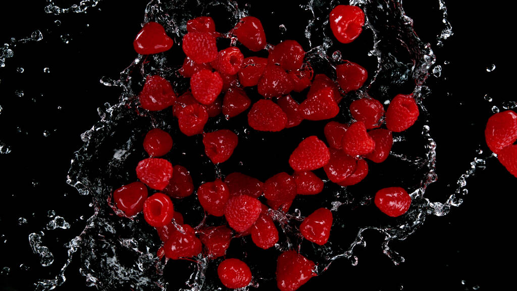 Freeze motion of raspberries in water splash. Isolated on Black Background. - Photo, Image