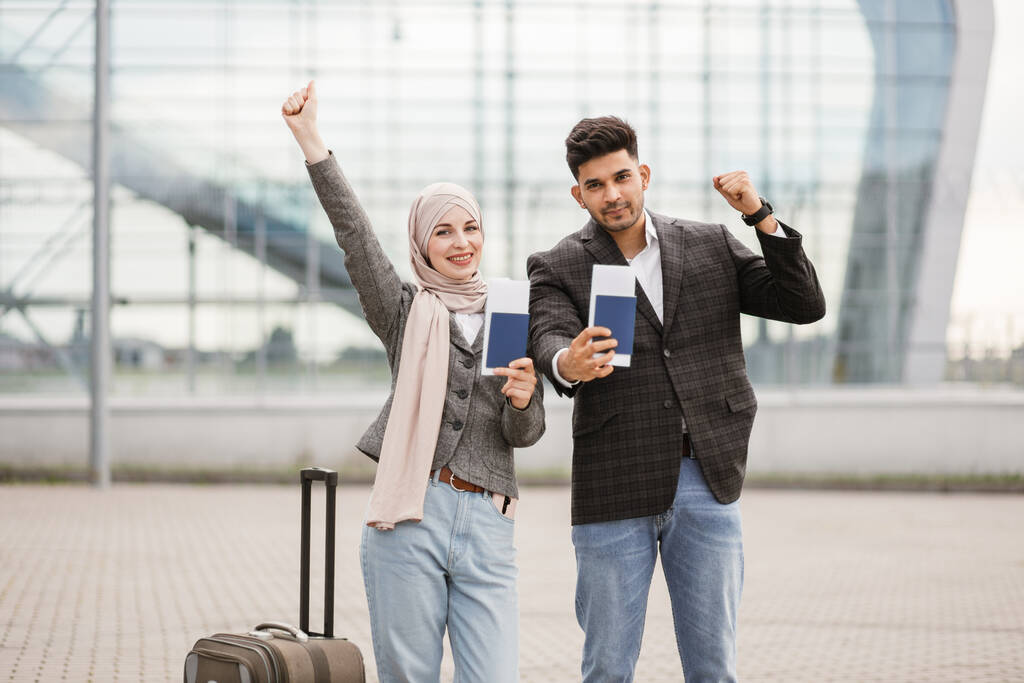 Moslim koppel, poseren op camera buiten het vliegveld, demonstreren hun paspoorten en tickets - Foto, afbeelding