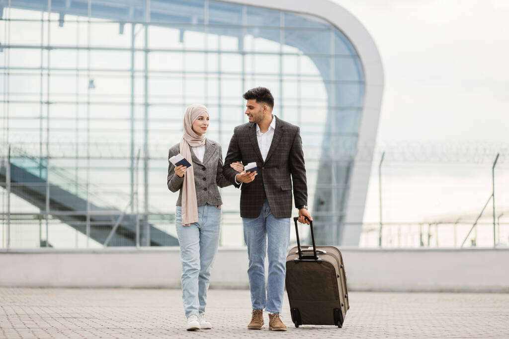 Мусульманка в хиджабе и арабский мужчина, выходящий на улицу с чемоданом и говорящий - Фото, изображение
