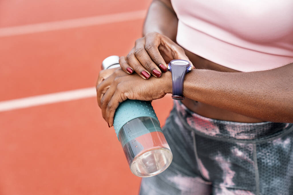 Sprinter schaut mit Wasserflasche auf die Uhr - Foto, Bild