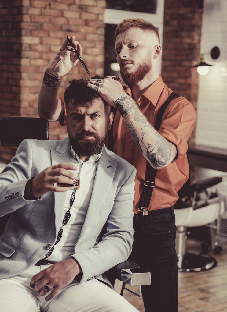 Idées sur Barbershop et salon de coiffure. Un type brutal dans un salon de coiffure moderne. Coiffeur fait coiffure un homme avec une barbe. Barbier - Rasages et garnitures. Soins de la barbe
. - Photo, image