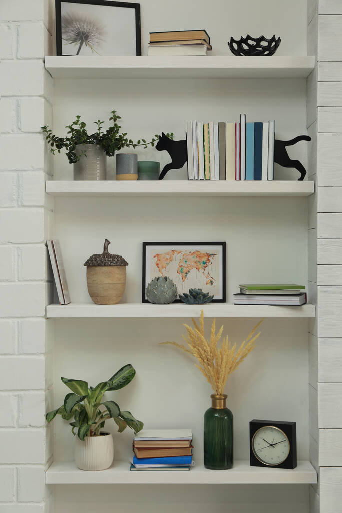 Φυλλάδια σε σχήμα γάτας με βιβλία και διαφορετική διακόσμηση σε ράφια σε εσωτερικούς χώρους. Εσωτερική διαρρύθμιση - Φωτογραφία, εικόνα