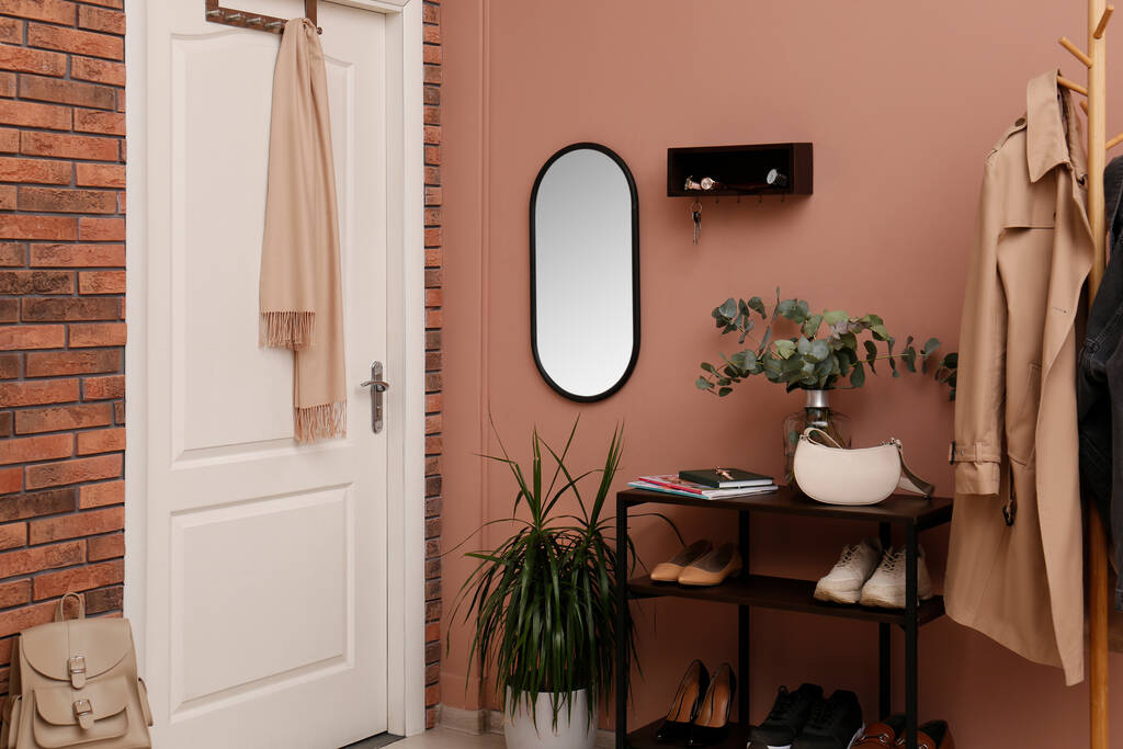 Interior del pasillo con plantas verdes y percha de madera para llaves en la pared rosa pálido - Foto, Imagen
