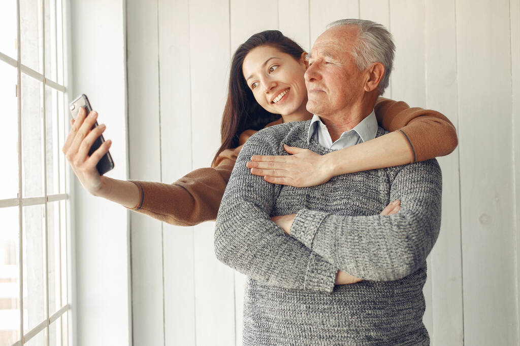 Eleganter alter Mann steht zu Hause bei seiner Enkelin - Foto, Bild