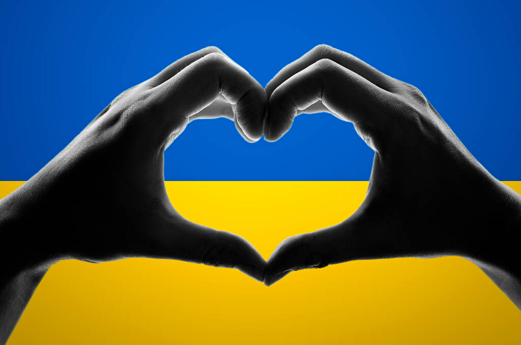 Руки в формі серця на українському прапорі. Допомога Україні під час війни - Фото, зображення
