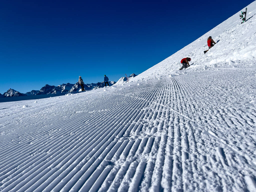 крупный план свежеухоженного снежного склона, небо безоблачное и голубое - Фото, изображение