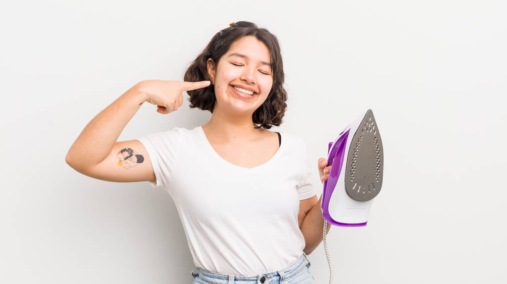 pretty hispanic girl smiling confidently pointing to own broad smile. laundry concept - Photo, Image