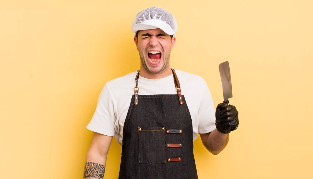 young handsome man shouting aggressively, looking very angry. butcher concept - Photo, Image