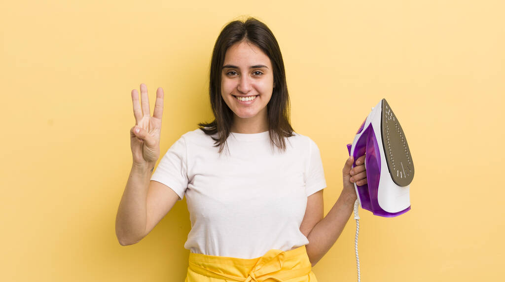 jeune femme hispanique souriante et amicale, montrant numéro trois. vêtements fer concept - Photo, image