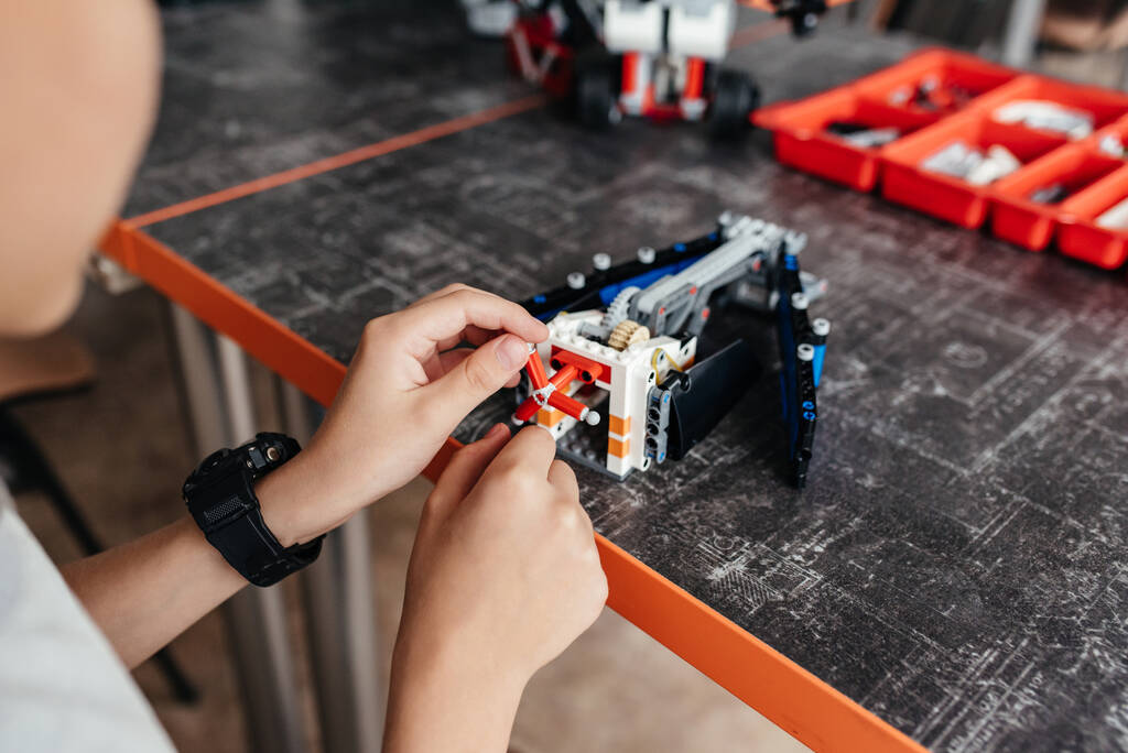 Крупный план мальчика, концентрирующегося на ремонте своих электронных роботов игрушек, играющих в строительство, создавая изобретение электроники робототехники технологии научного образования хобби досуга детей - Фото, изображение
