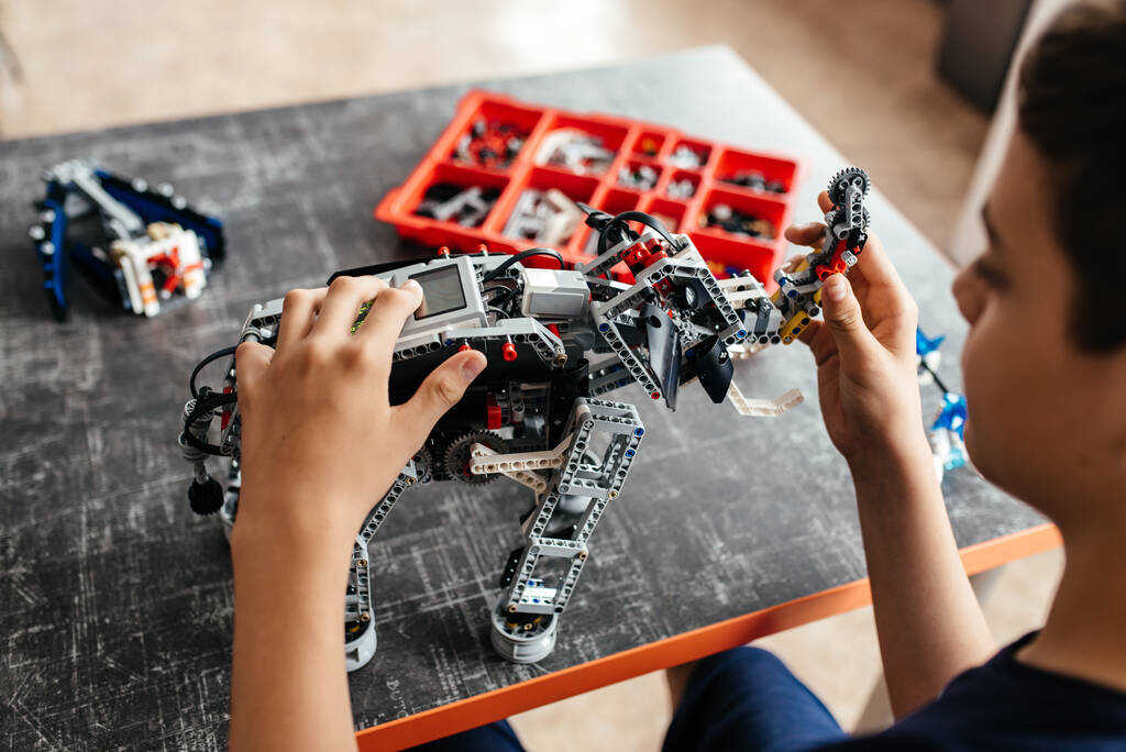 futuri ingegneri e progettisti. i bambini caucasici cercano di collegare i fili e assemblare robot isolati - Foto, immagini