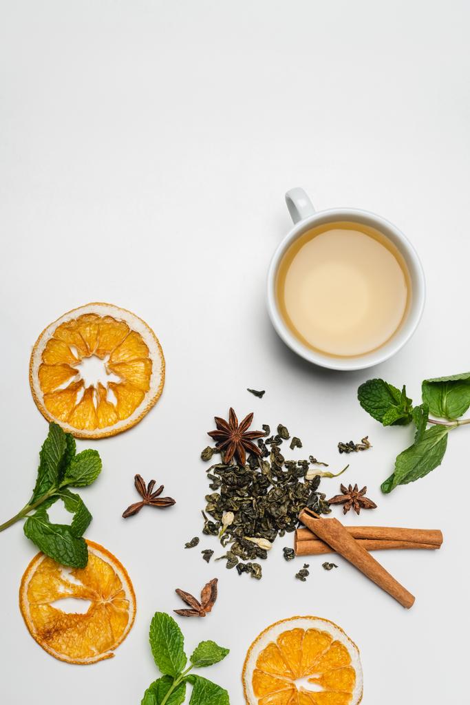 ミントの近くのお茶のカップのトップビュー,スパイスや白の背景に乾燥オレンジスライス  - 写真・画像