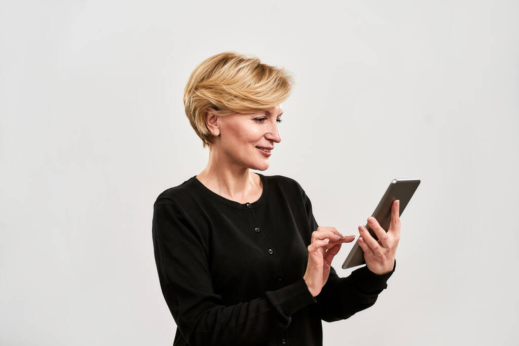 Volwassen vrouw met en kijken op digitale tablet - Foto, afbeelding