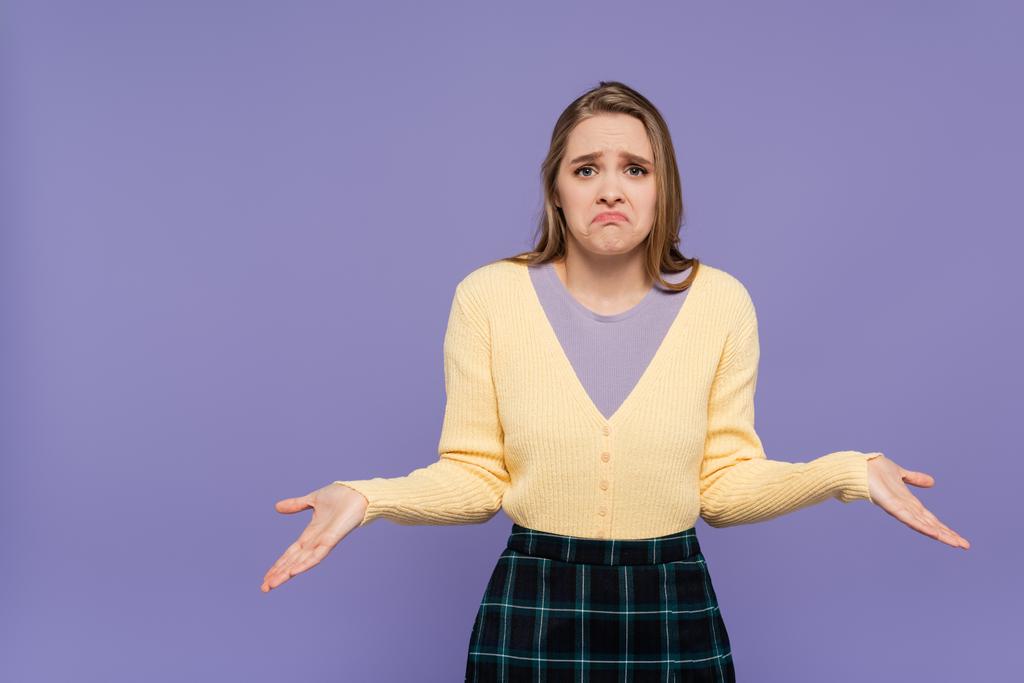 confused young woman looking at camera while gesturing isolated on purple - Photo, Image