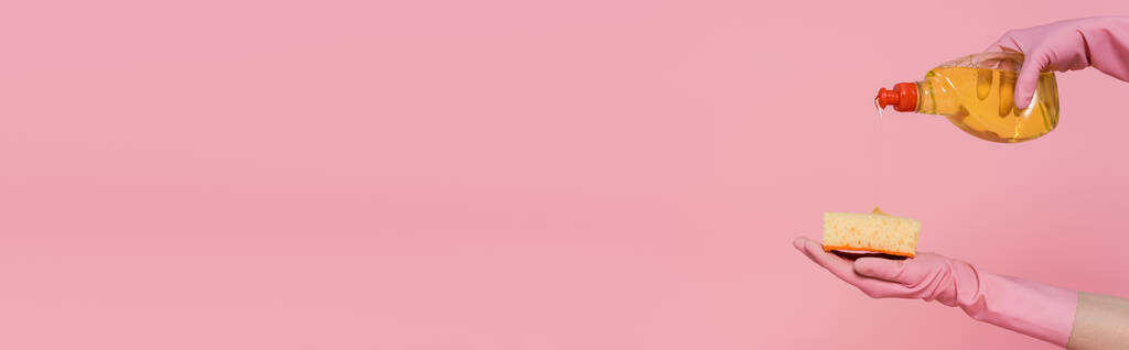καλλιεργημένη άποψη της γυναίκας ρίχνει απορρυπαντικό σε σφουγγάρι απομονώνονται σε ροζ, πανό - Φωτογραφία, εικόνα
