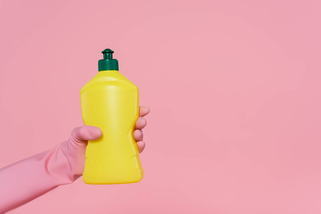 vista ritagliata di donna che tiene bottiglia gialla con detergente isolato su rosa  - Foto, immagini