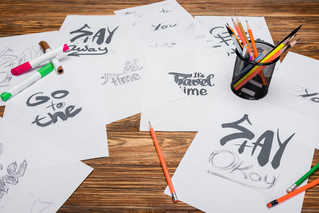бумаги с разными словами и фразами, войлочные ручки и цветные карандаши на деревянном столе - Фото, изображение