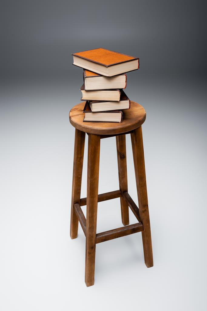 tabouret en bois avec pile de livres sur fond gris - Photo, image