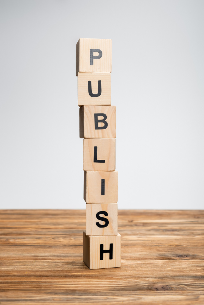 stack of cubes with publish lettering on wooden surface isolated on grey - Photo, Image
