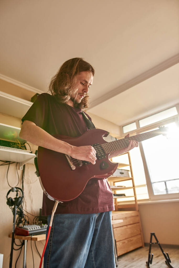 Bottom view van de mens spelen elektrische gitaar thuis - Foto, afbeelding