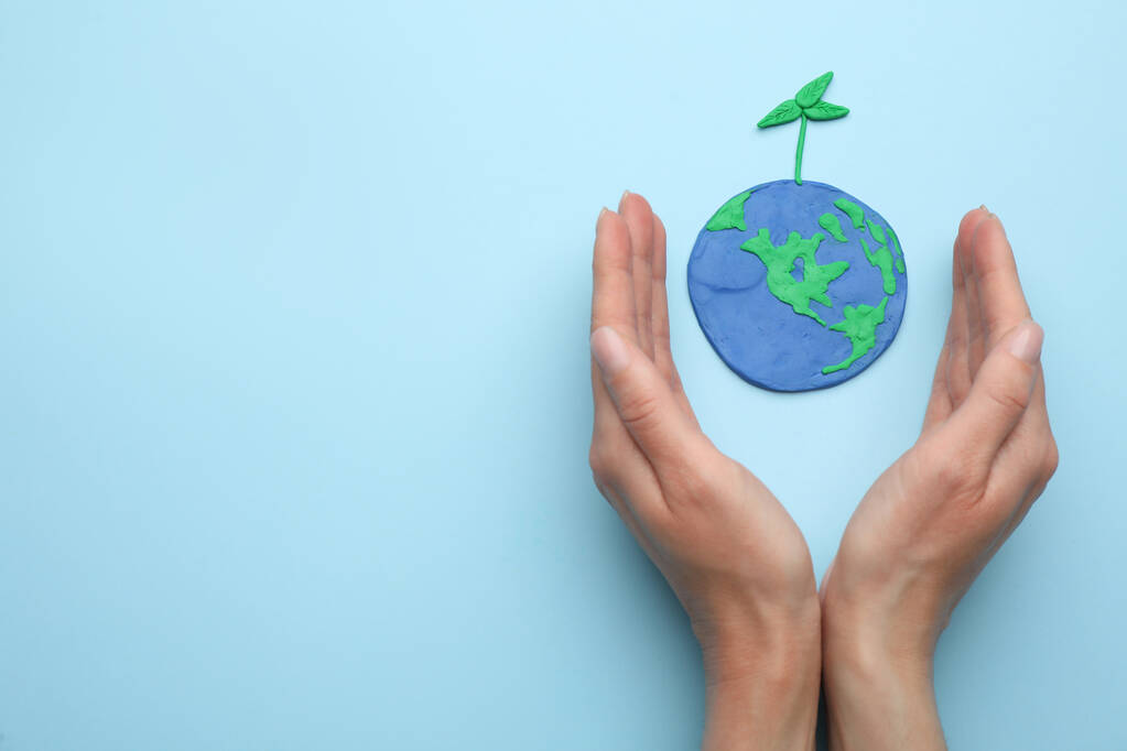 Femme près du modèle de plasticine de la planète avec semis vert et espace pour le texte sur fond bleu clair, vue du dessus. Jour de la Terre - Photo, image