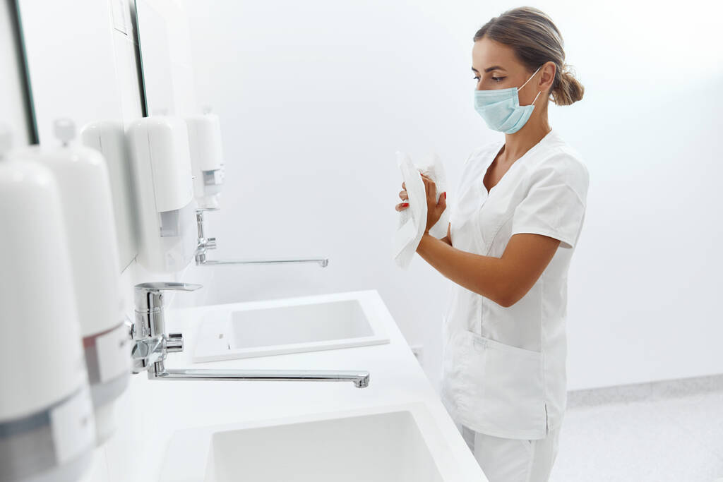 Igiene, assistenza sanitaria. Ritratto di donna medico o infermiere che si asciuga le mani con carta velina in ospedale dopo aver lavato le mani - Foto, immagini