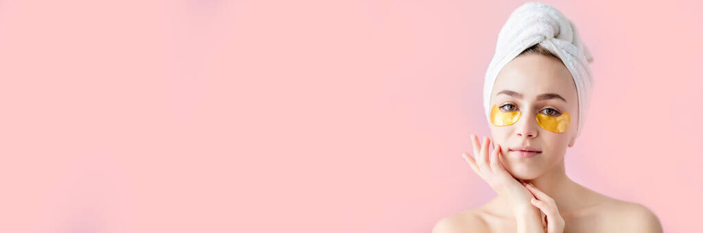 Πορτρέτο της γυναίκας ομορφιάς με μπαλώματα ματιών σε ροζ φόντο. Γυναίκα όμορφο πρόσωπο με μάσκα κάτω από τα μάτια. Όμορφη γυναίκα με φυσικό μακιγιάζ και χρυσά καλλυντικά κολλαγόνο μπαλώματα σε φρέσκο δέρμα προσώπου - Φωτογραφία, εικόνα