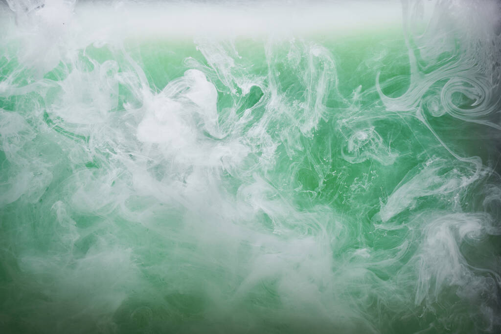 Πράσινος καπνός σε λευκό φόντο μελάνι, πολύχρωμη ομίχλη, αφηρημένη στροβιλίζονται σμαραγδένια θάλασσα του ωκεανού, ακρυλικό χρώμα υποθαλάσσια χρωστική - Φωτογραφία, εικόνα