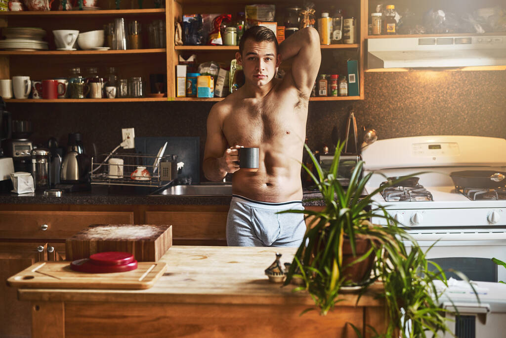 Élvezem a kávét a konyhában. Vágott felvétel egy jóképű, fiatal félmeztelen férfiról, aki egy csésze kávét iszik otthon a konyhában.. - Fotó, kép