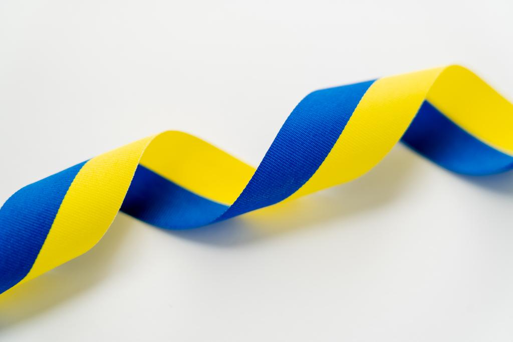 Vue rapprochée du ruban bleu et jaune bouclé sur fond blanc  - Photo, image
