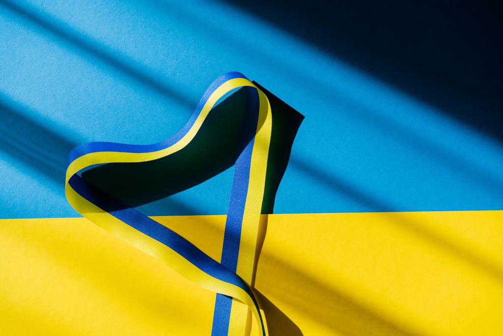 Top view of ribbon in heart shape with shadow on ukrainian flag - Photo, Image