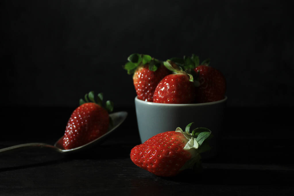 fresas frescas en un tazón sobre un fondo negro - Foto, Imagen