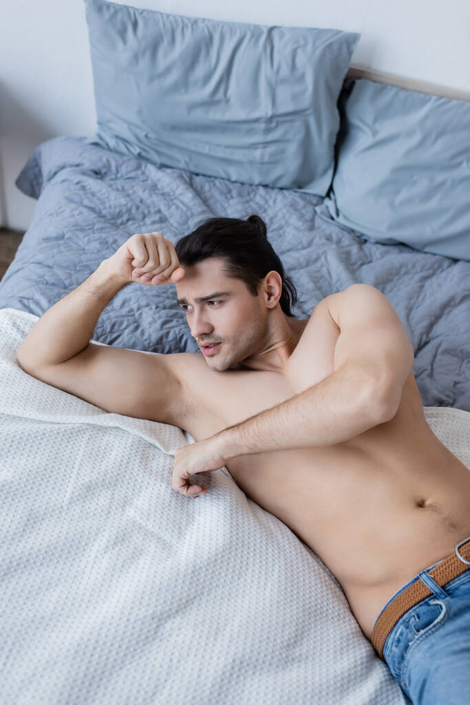 korkea kulma näkymä paidaton mies makaa sängyllä - Valokuva, kuva
