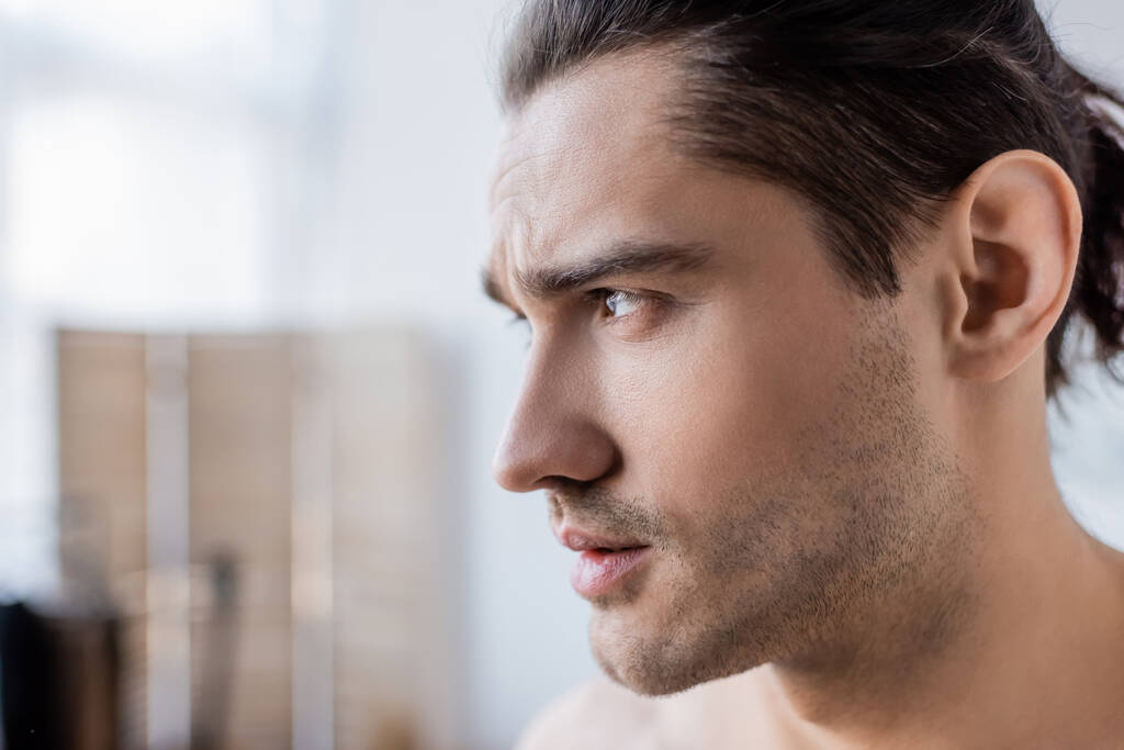 close up de homem com cabelos longos olhando para longe em casa - Foto, Imagem