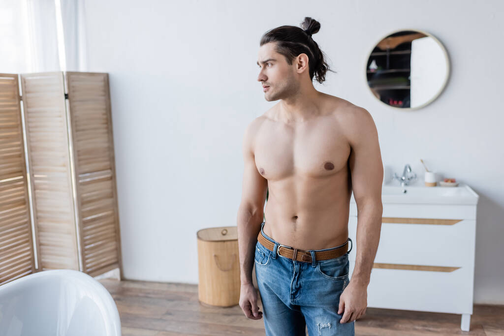 uomo senza maglietta con i capelli lunghi in piedi in bagno moderno  - Foto, immagini