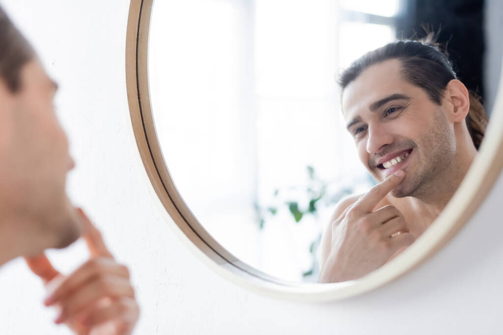 Mutlu ve üstsüz bir adam banyoda aynaya bakarken gülümsüyor.  - Fotoğraf, Görsel