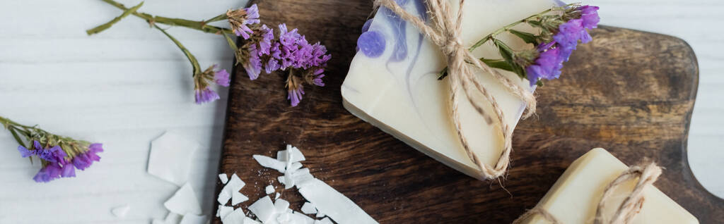 Draufsicht auf Craft-Soap-Bar mit Blumen auf Schneidebrett auf Tisch, Banner  - Foto, Bild