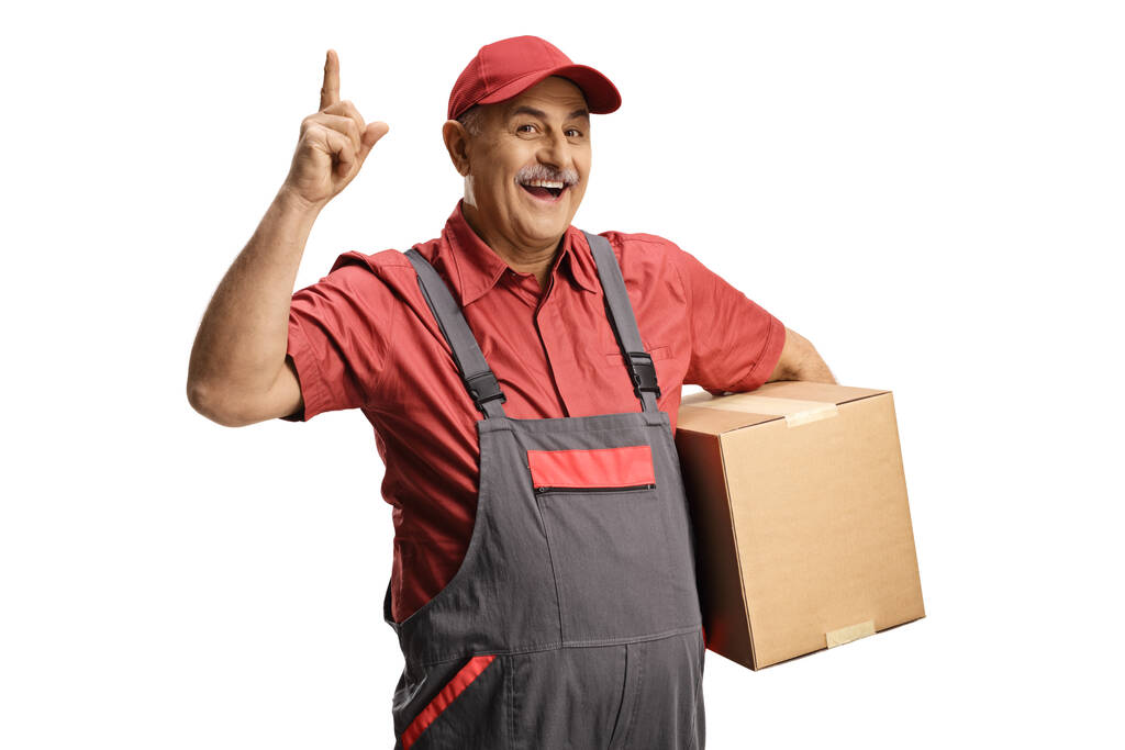 Homme de livraison mature tenant une boîte en carton et pointant vers le haut isolé sur fond blanc  - Photo, image