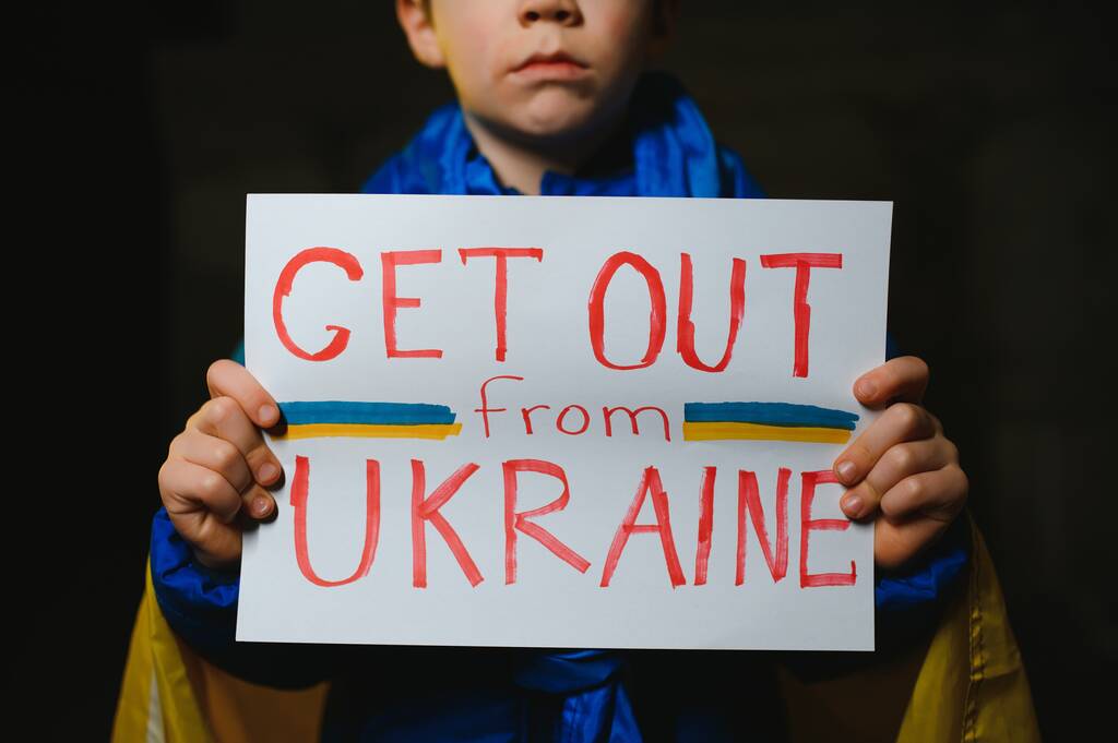 Upset Ukrainian poor toddler boy kid homeless protesting war conflict raises banner with inscription massage text No War on black background. Crisis, peace, stop aggression, child against Russian war - Photo, Image