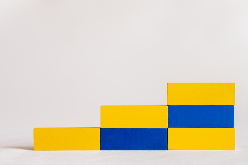 escaleras hechas de bloques rectangulares azules y amarillos sobre fondo blanco, concepto ucraniano - Foto, Imagen