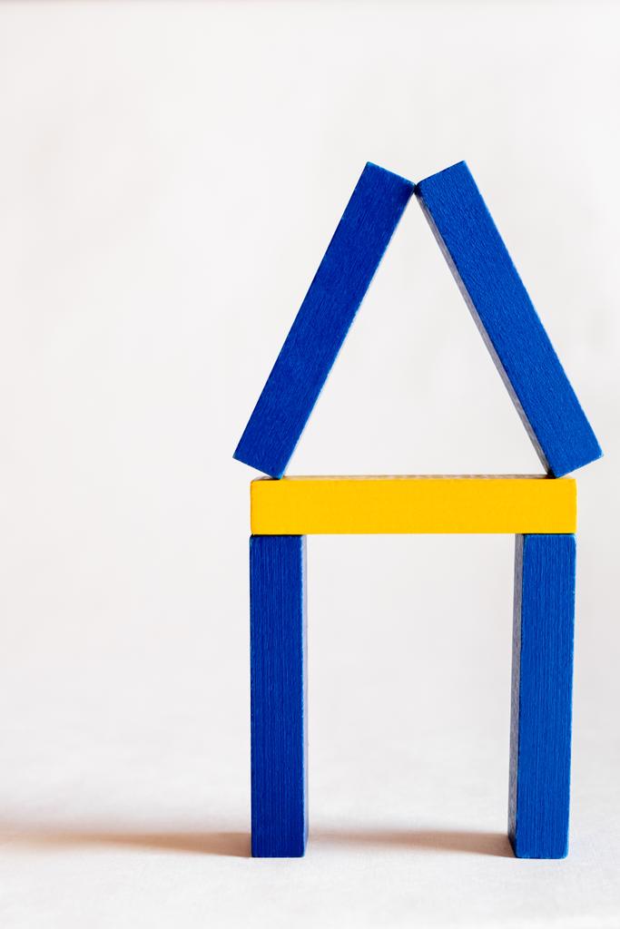 символ будинку зроблений з синього і жовтого блоків на білому тлі, україніанська концепція - Фото, зображення