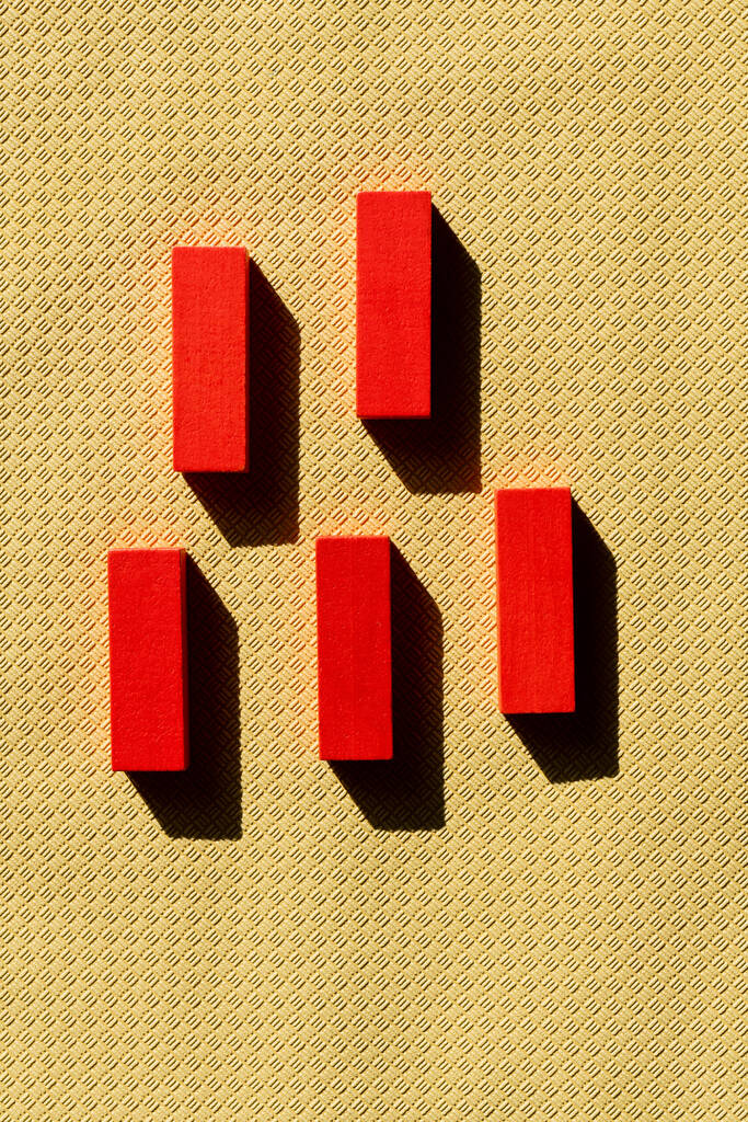 вид зверху яскраво-червоних блоків на бежевому текстурованому фоні з тінями
 - Фото, зображення