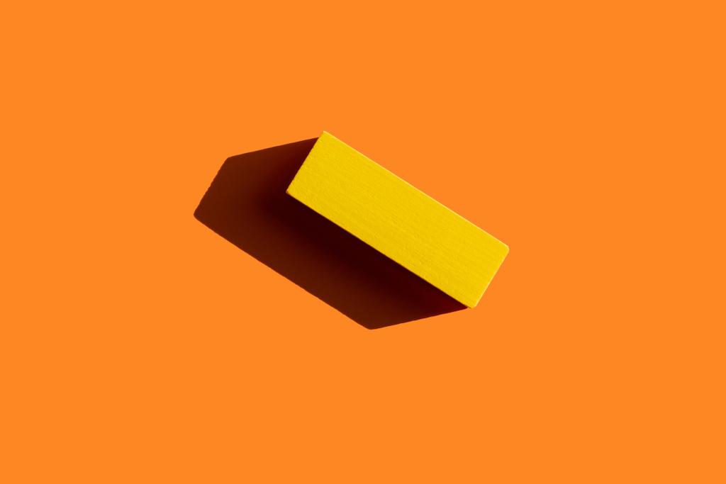 top view of colored yellow block on orange background with shadow - Photo, Image