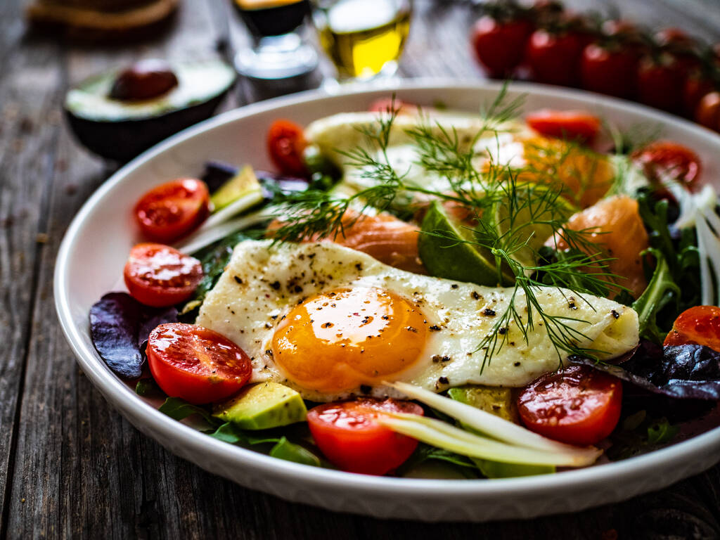 Salade de saumon - saumon fumé, œufs d'accompagnement ensoleillés, avocat et légumes frais sur table en bois  - Photo, image