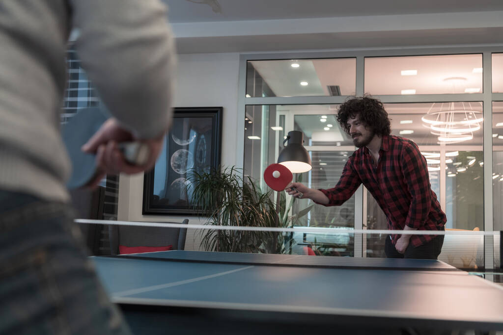 Due giovani start up uomo d'affari che giocano a ping pong nel moderno spazio creativo ufficio gruppo di persone hanno riunione e brainstorming in background
 - Foto, immagini