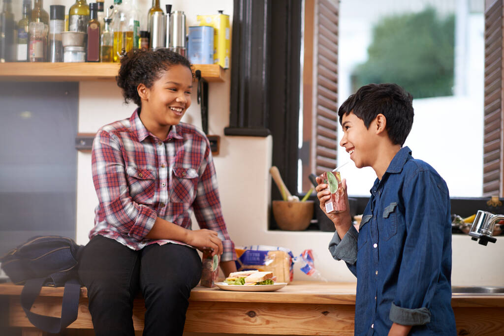 Mangiare un bocconcino gustoso dopo scuola. Girato di due giovani adolescenti che si godono uno spuntino insieme in cucina. - Foto, immagini